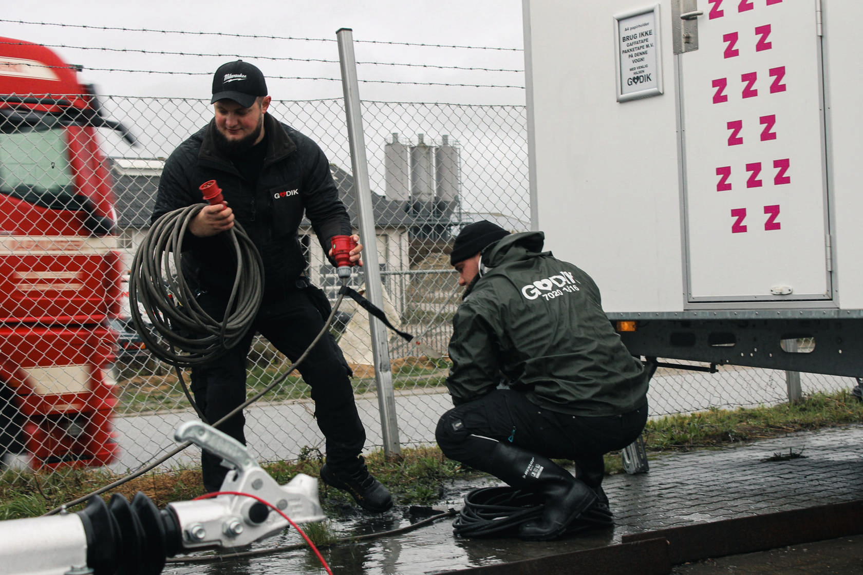 Godik-medarbejdere tilslutter strøm og håndterer kabler ved et udendørs anlæg