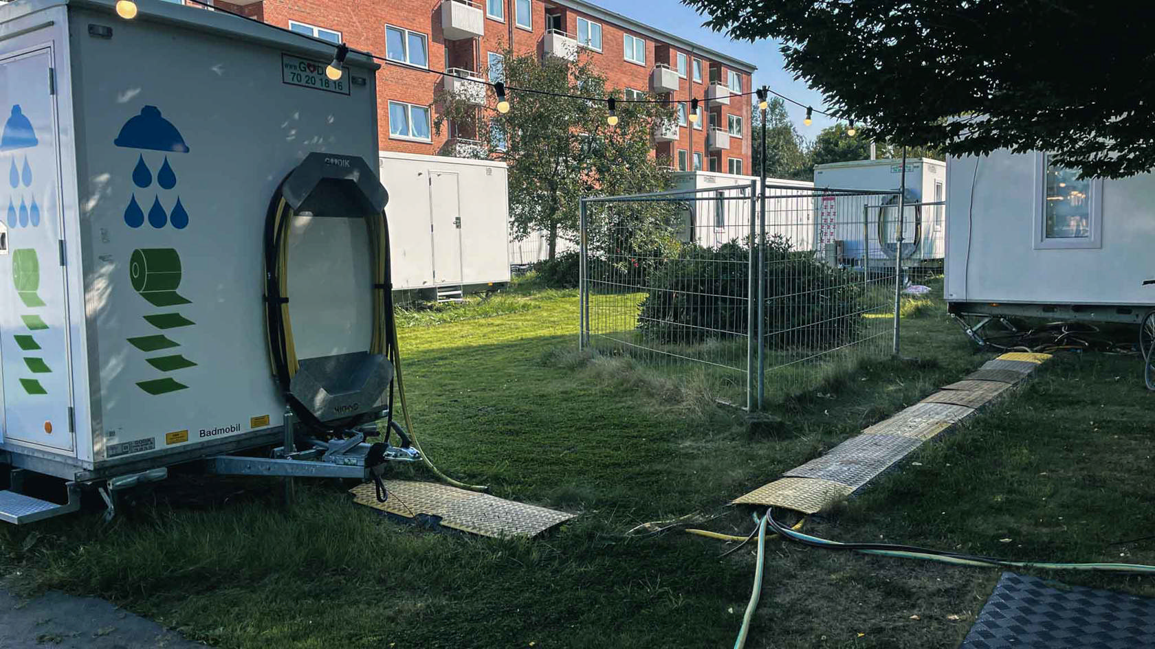Godik bade- og toiletvogne og beboelsesvogne foran et lejlighedskompleks i forbindelse med renovering og genhusning